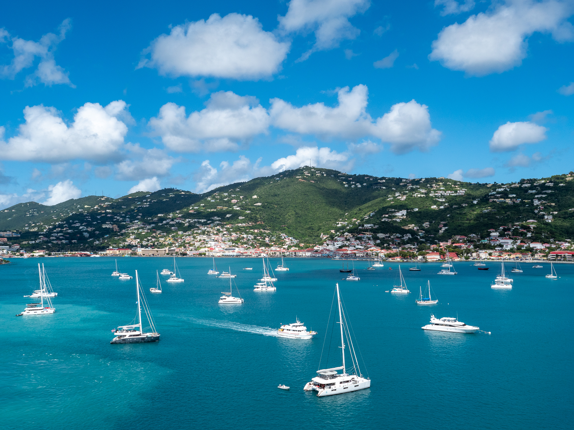 Turquoise harbor with boats and green hills